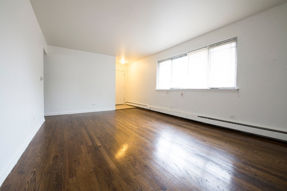 an empty living room with wood floors and a window