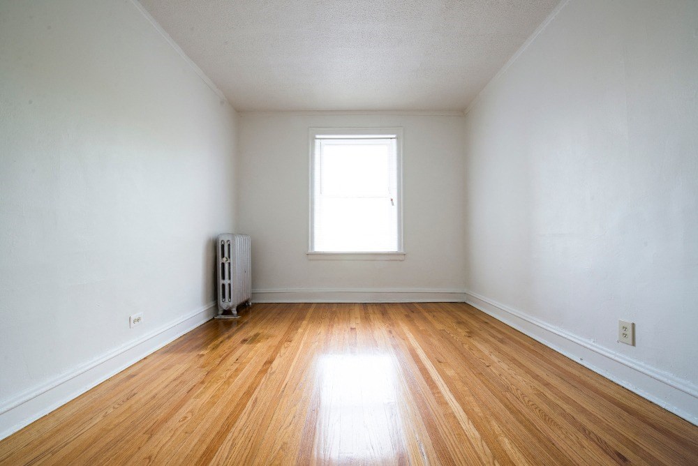 an empty room with white walls and a window and wooden floors