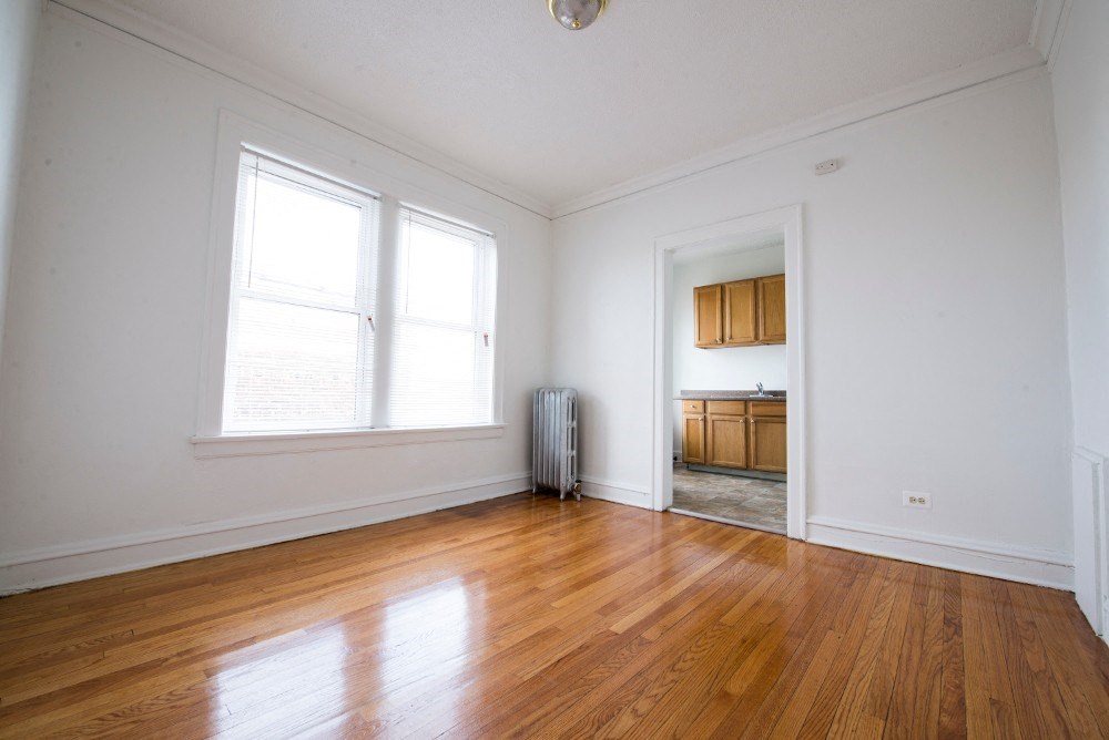 an empty living room with a hard wood floor and two windows