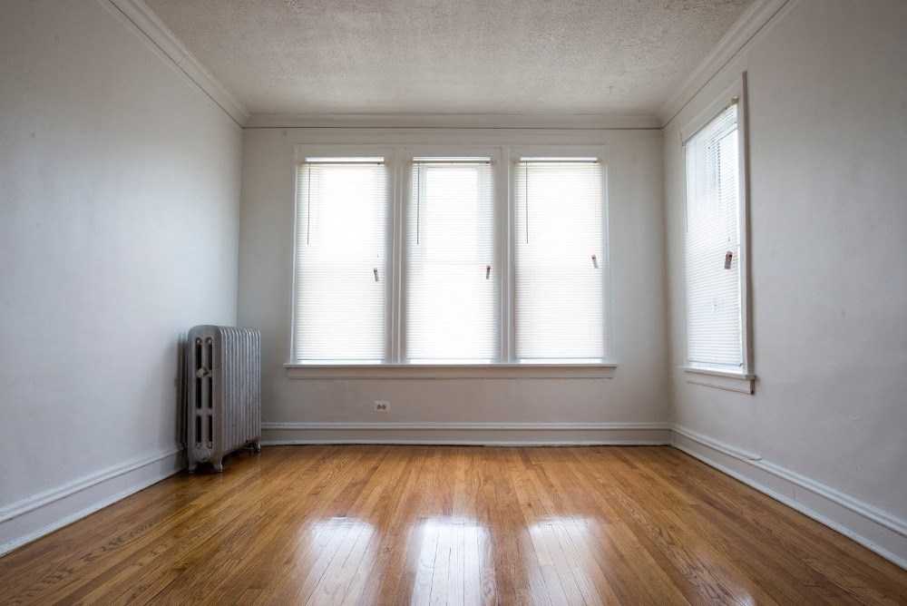 an empty room with wooden floors and three windows