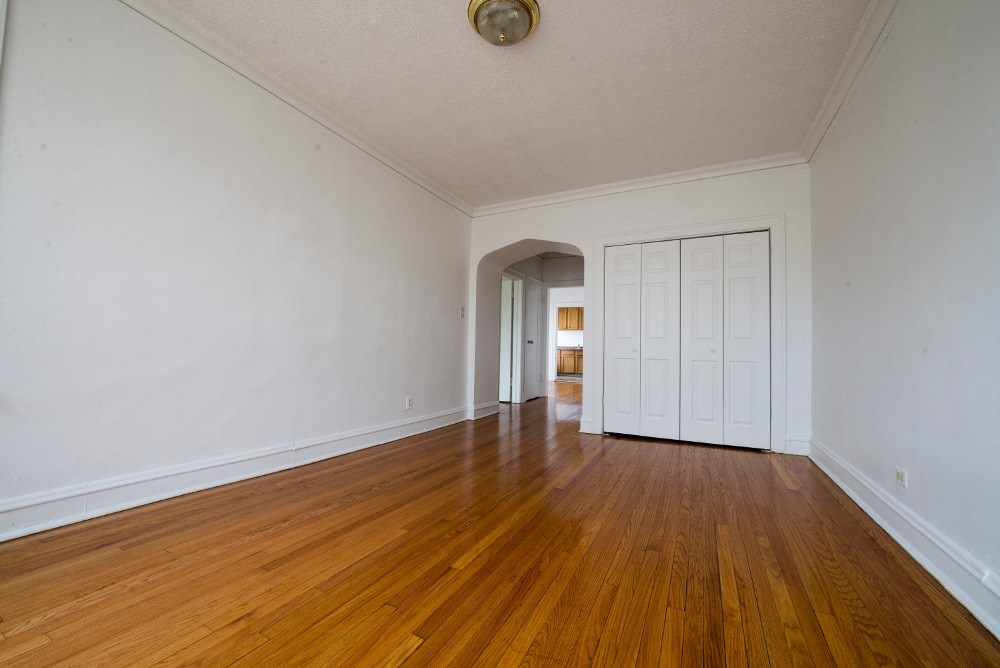 an empty living room with wood floors and white walls