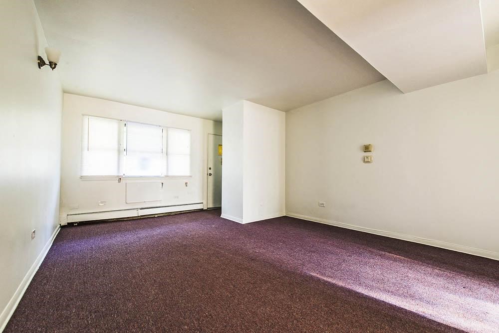 an empty room with purple carpet and a window