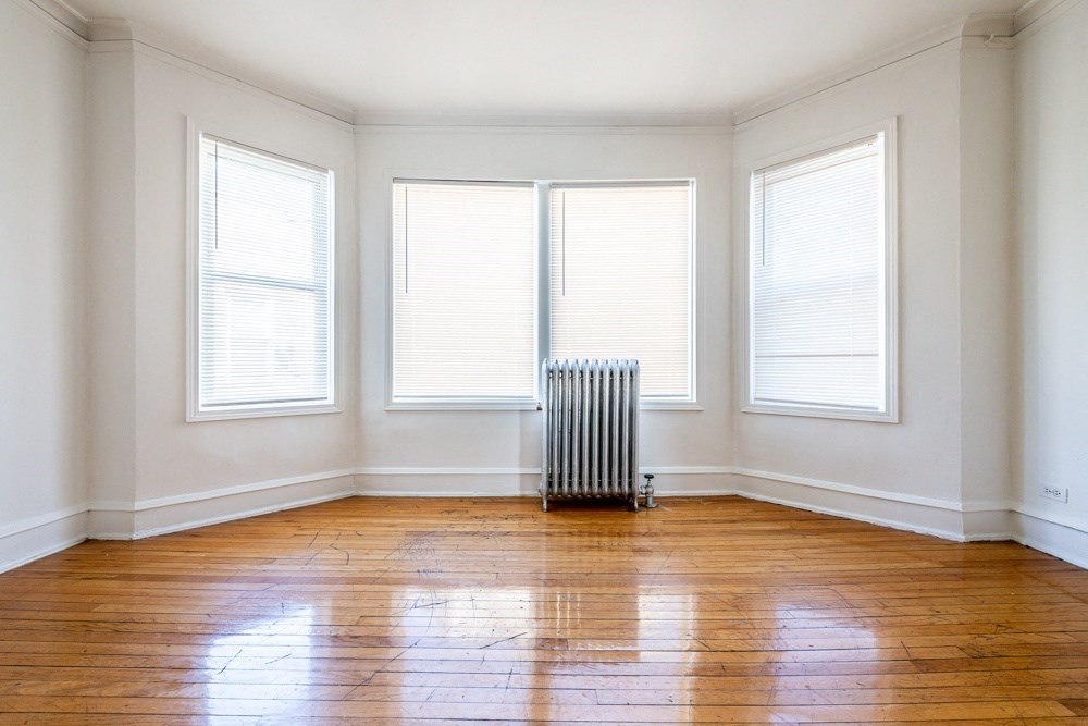 an empty room with a radiator and three windows