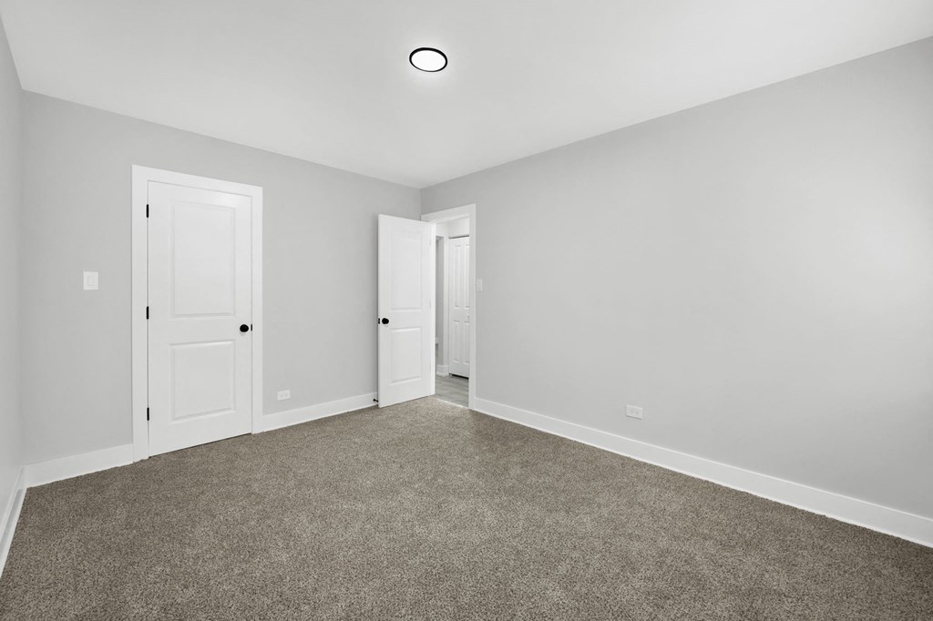 a bedroom with grey carpet and white walls