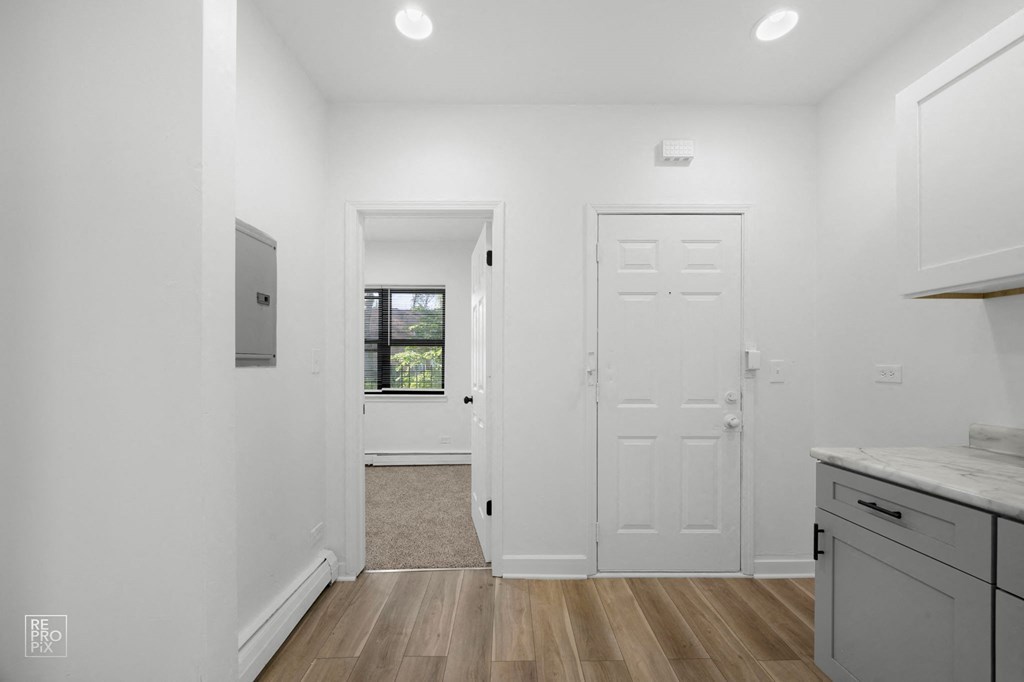 a kitchen with white walls and white cabinets and a white door