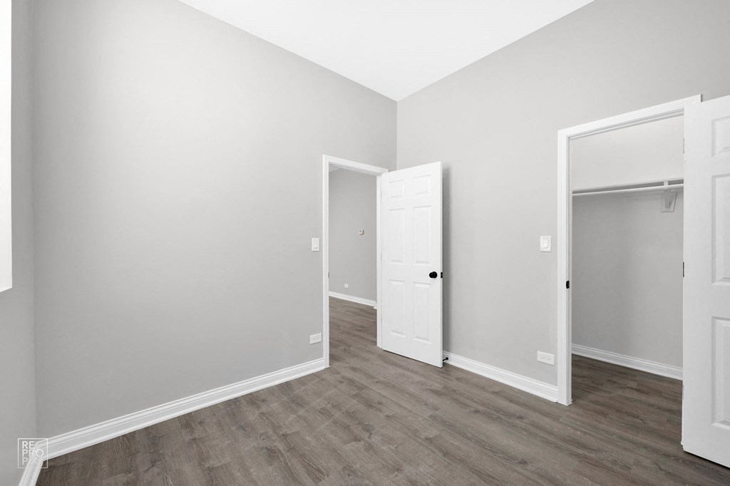 a bedroom with gray walls and hardwood floors