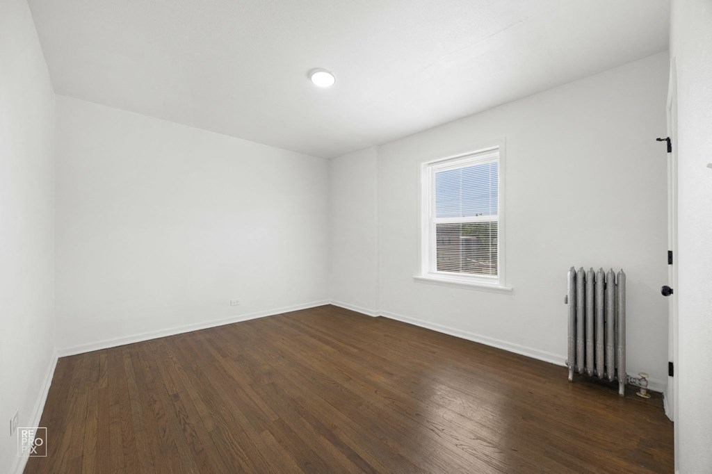 a living room with white walls and wood floors and a radiator