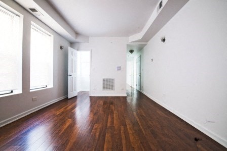 an empty living room with wood floors and white walls