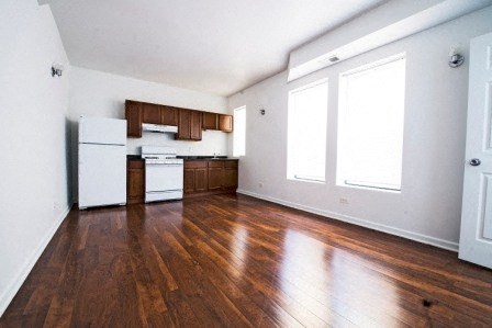 an empty kitchen with wood floors and white appliances