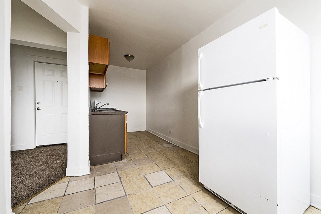 an empty kitchen with a refrigerator and a sink
