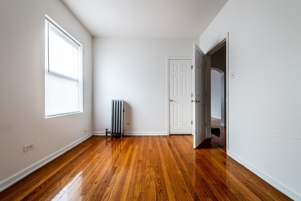 an empty room with wood floors and a radiator and a door