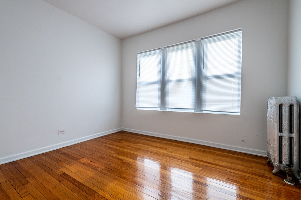 an empty room with wooden floors and white walls and a window