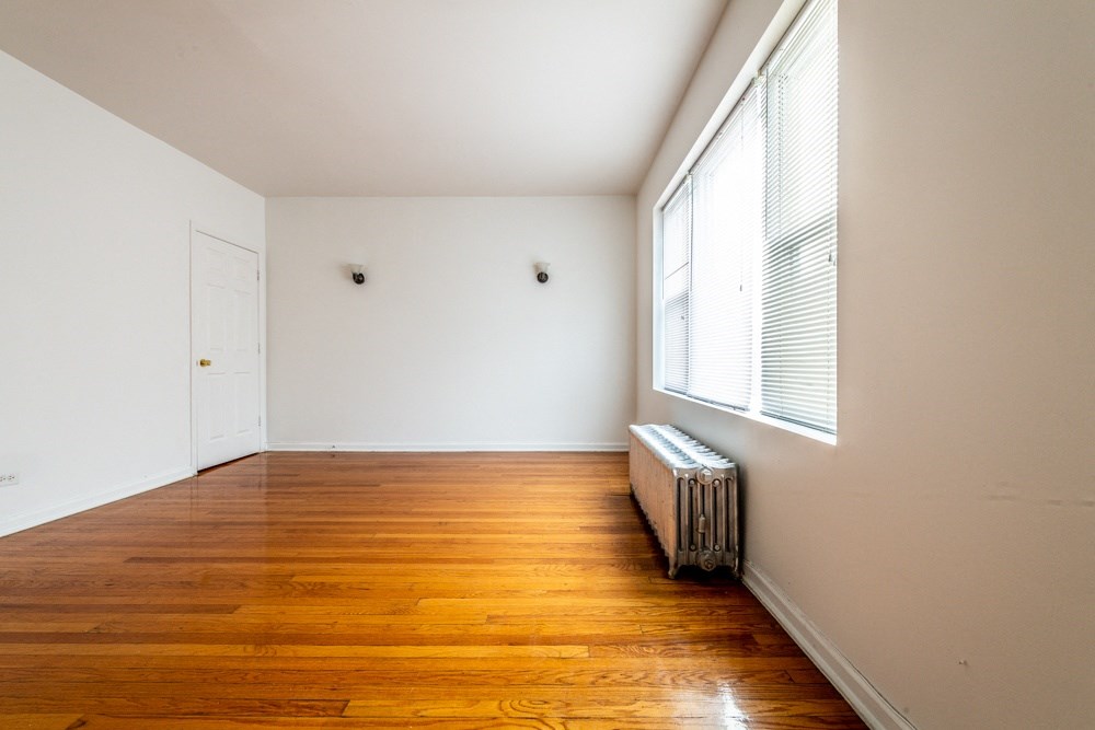 an empty living room with wood floors and a large window