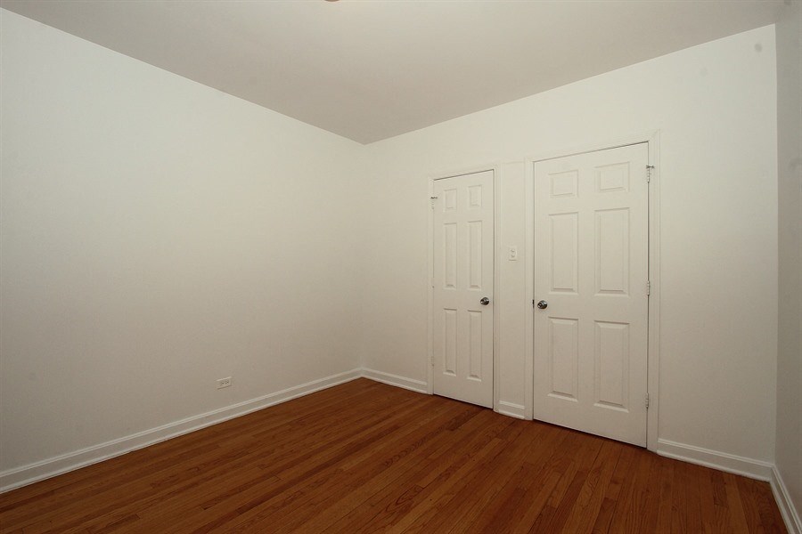 a bedroom with two white doors and a wood floor