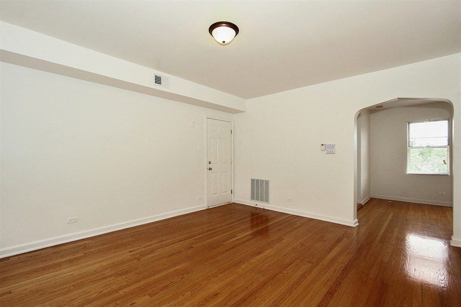 an empty living room with wood floors and a door to a hallway