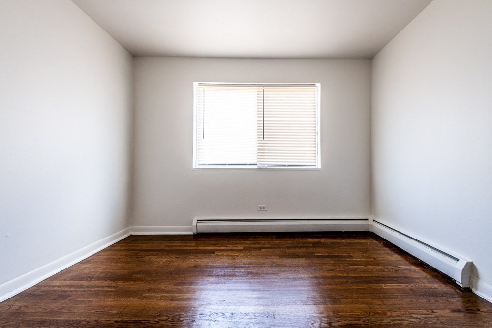 an empty room with wooden floors and a window