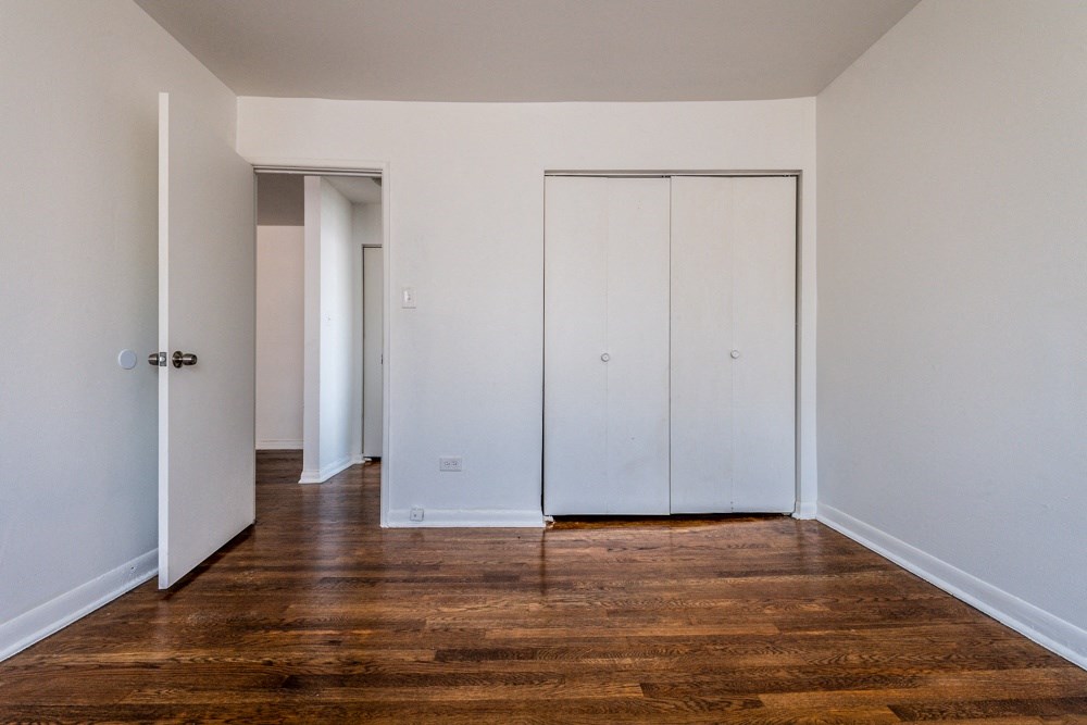 an empty room with white walls and wood floors and a closet