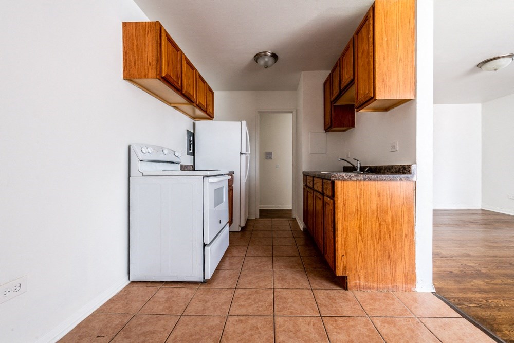 an empty kitchen with a white refrigerator and a sink