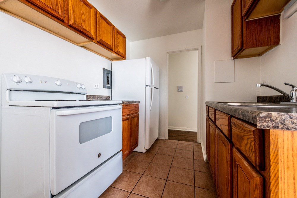an empty kitchen with a stove refrigerator and sink