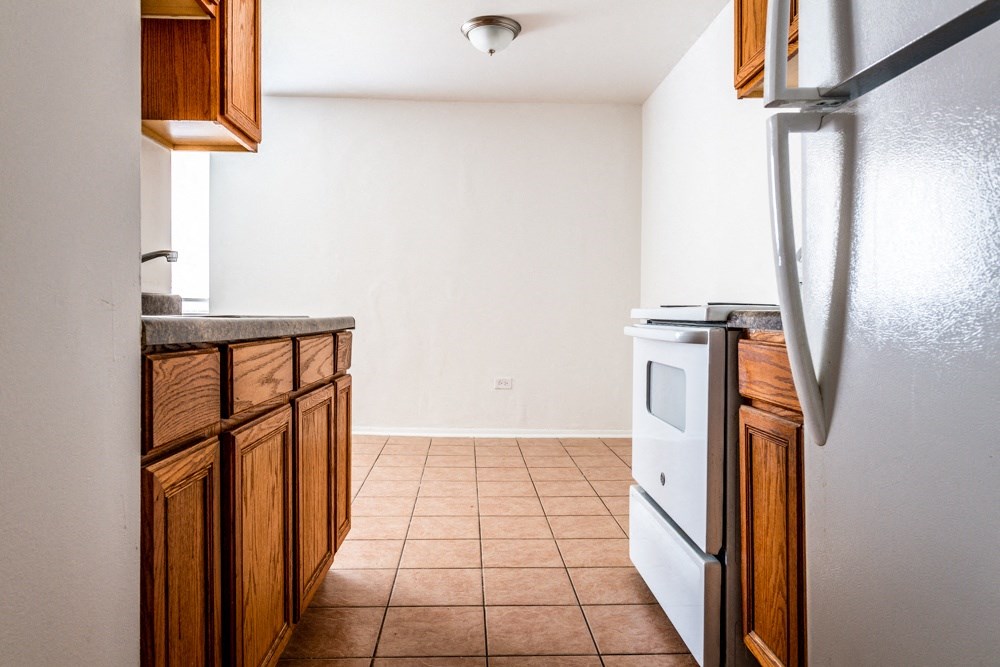 an empty kitchen with white appliances and wooden cabinets