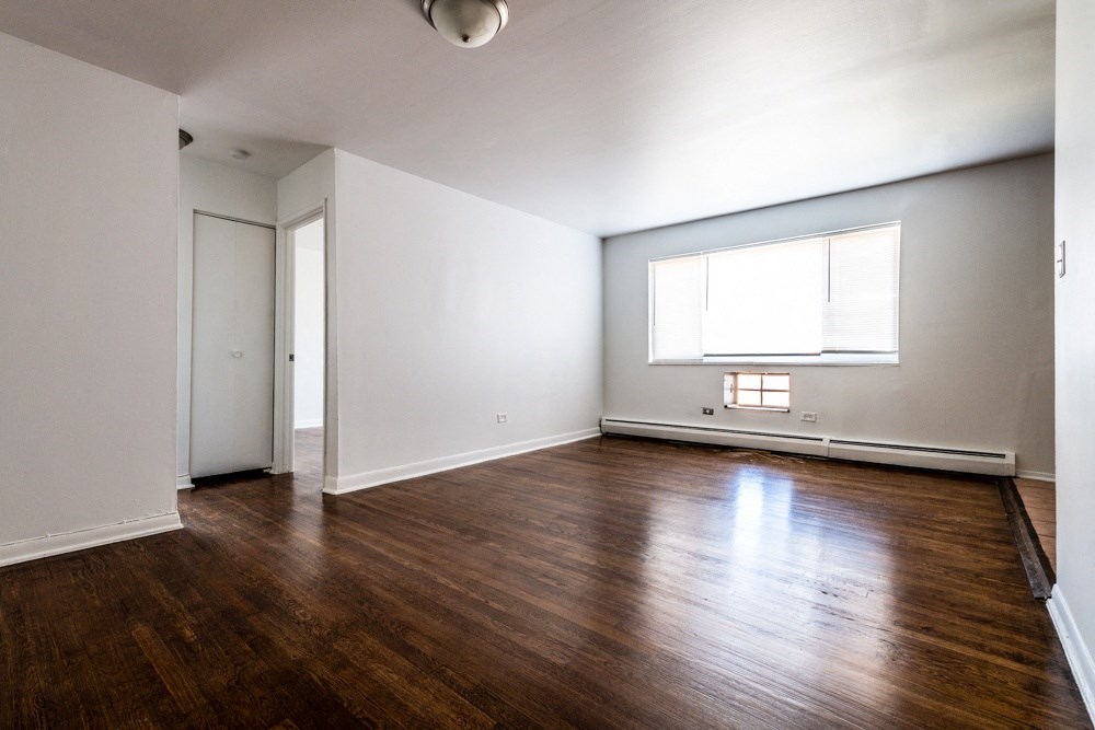 an empty living room with wood floors and a window