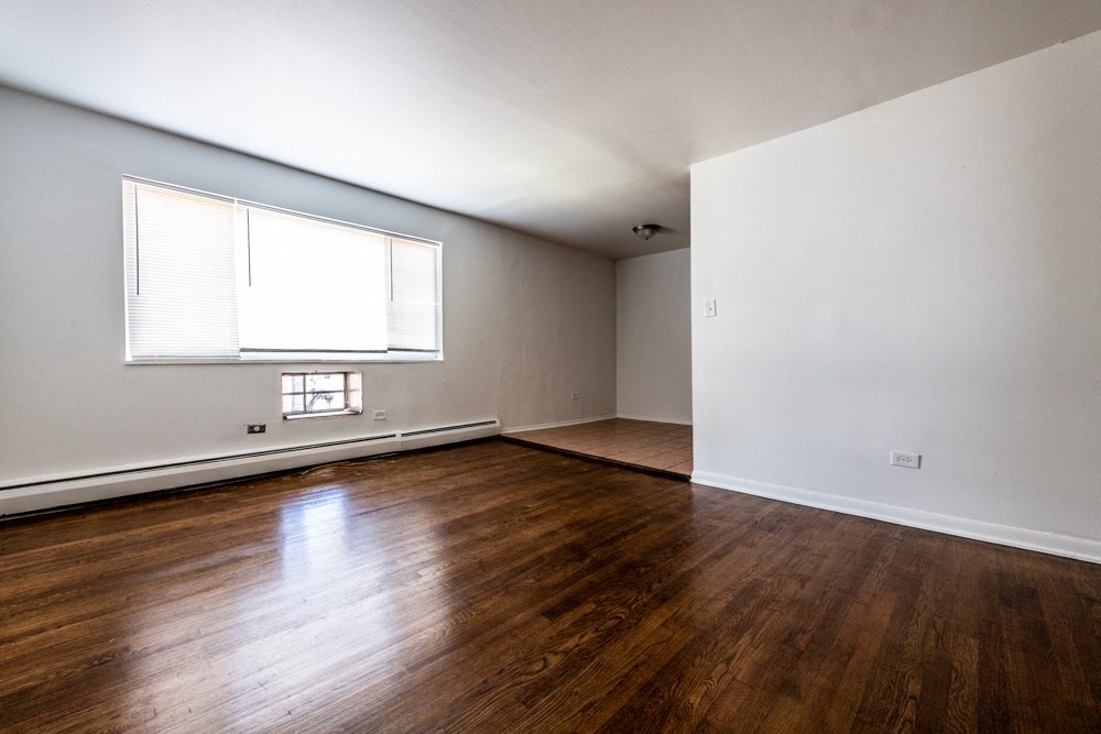 an empty living room with wood floors and a window