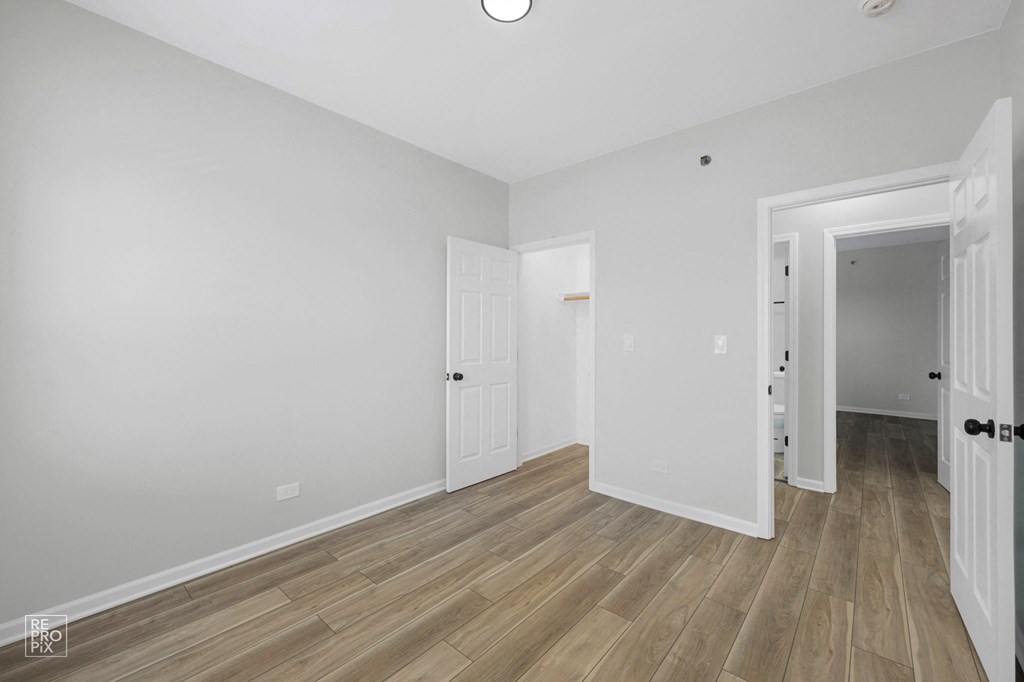 a bedroom with hardwood floors and grey walls