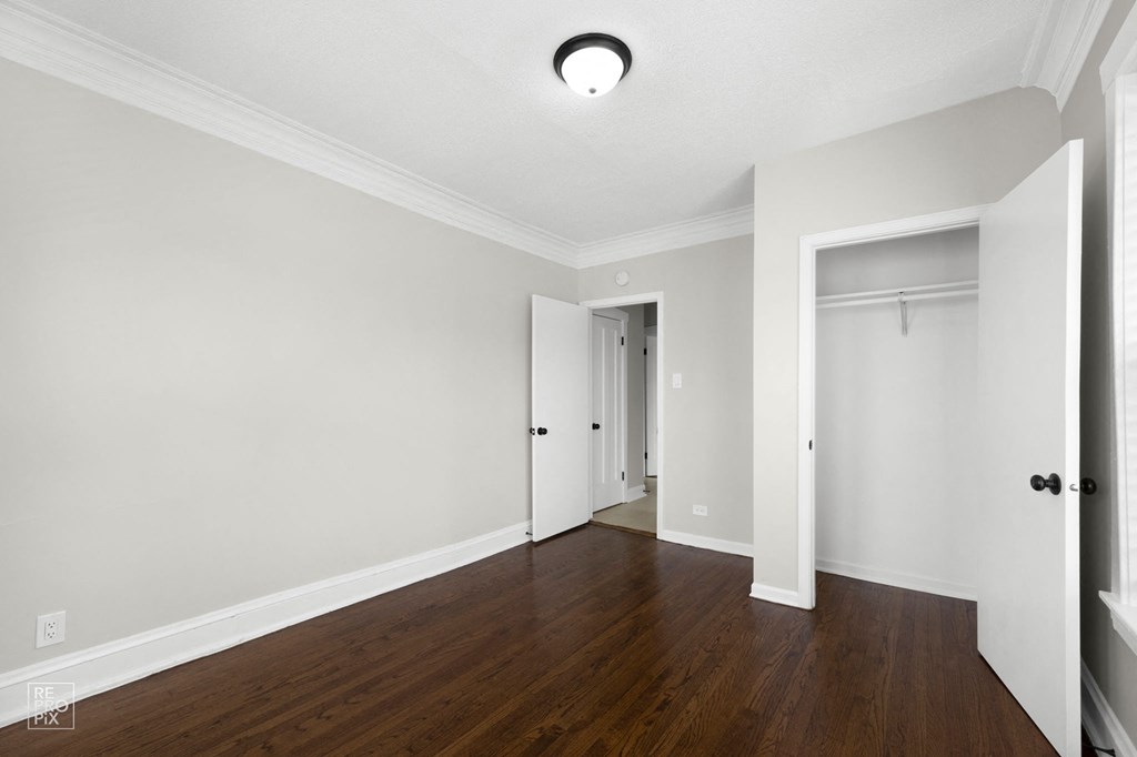 a bedroom with hardwood floors and grey walls