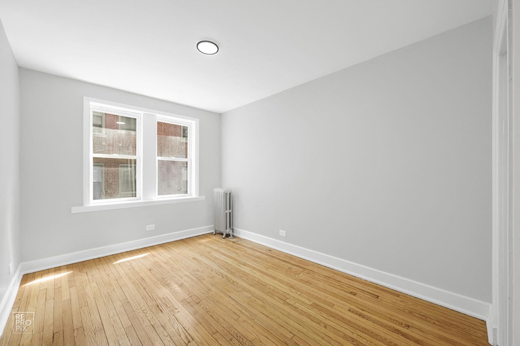 an empty room with two windows and a radiator