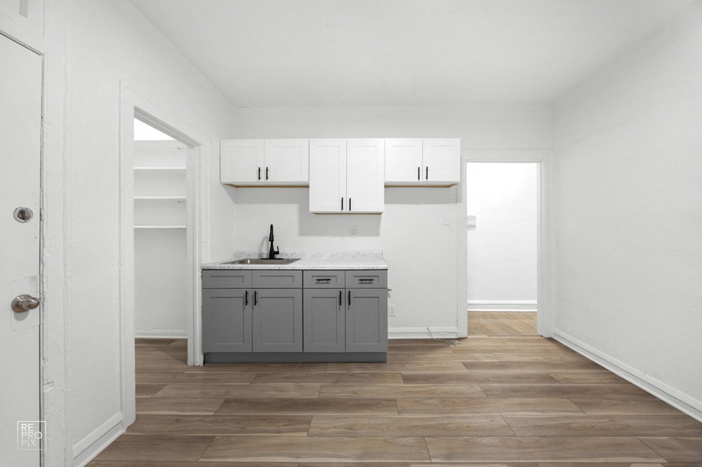 a kitchen with white walls and a wooden floor