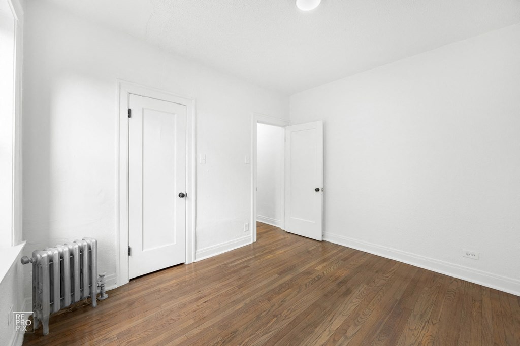 a living room with white walls and wooden floors and white doors