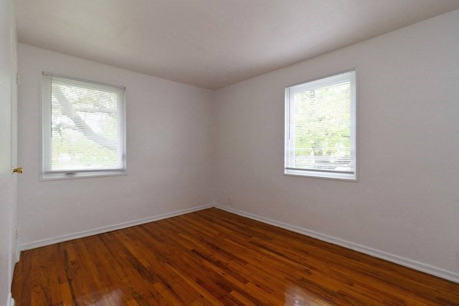 an empty room with a wooden floor and two windows