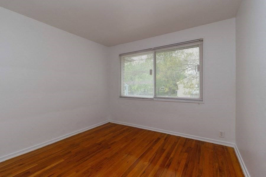 an empty room with a window and wooden floors