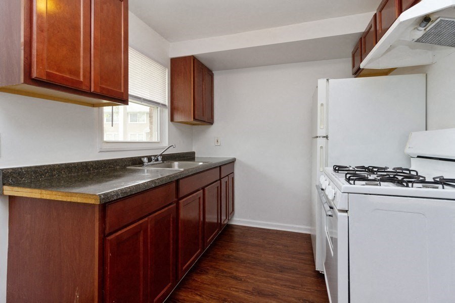 an empty kitchen with white appliances and wooden cabinets