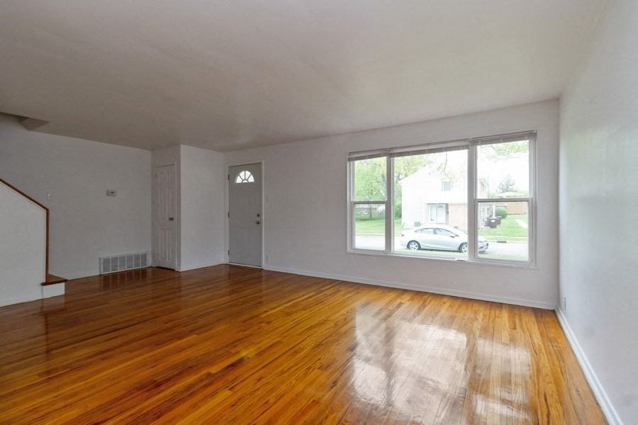 an empty living room with wood floors and a large window