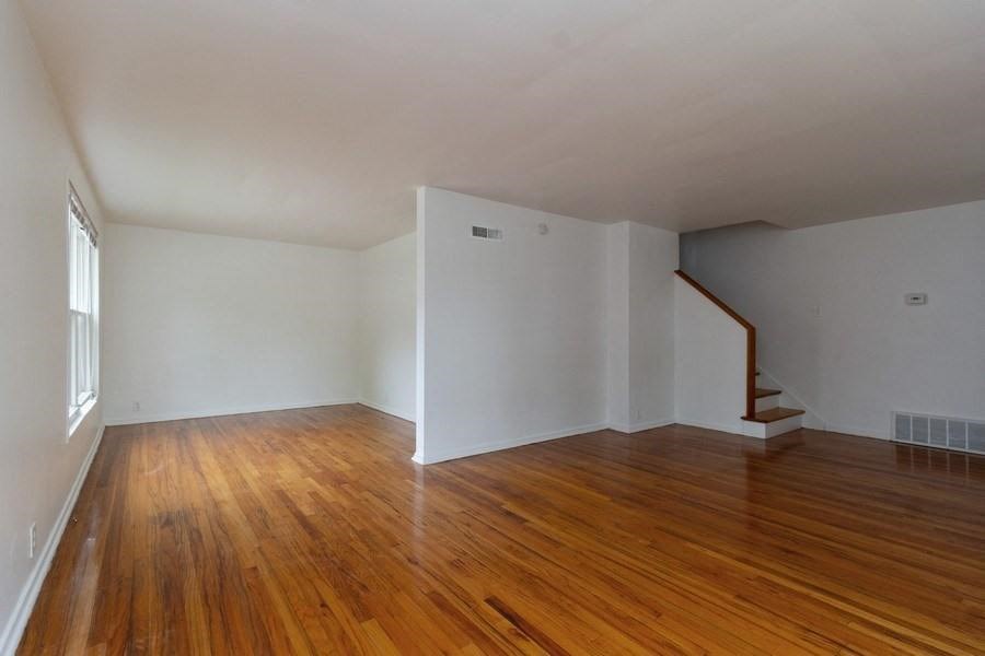 an empty living room with wood floors and a staircase
