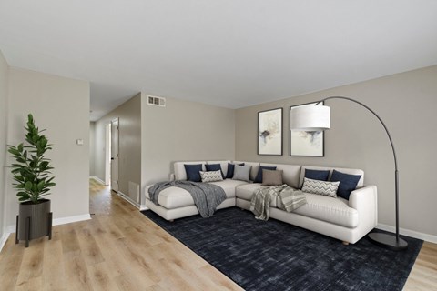 A modern living room with a white sofa and a wooden floor.