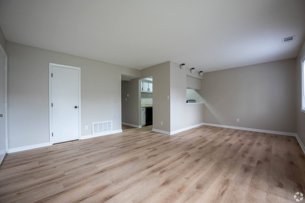 an empty living room with wood floors and white walls