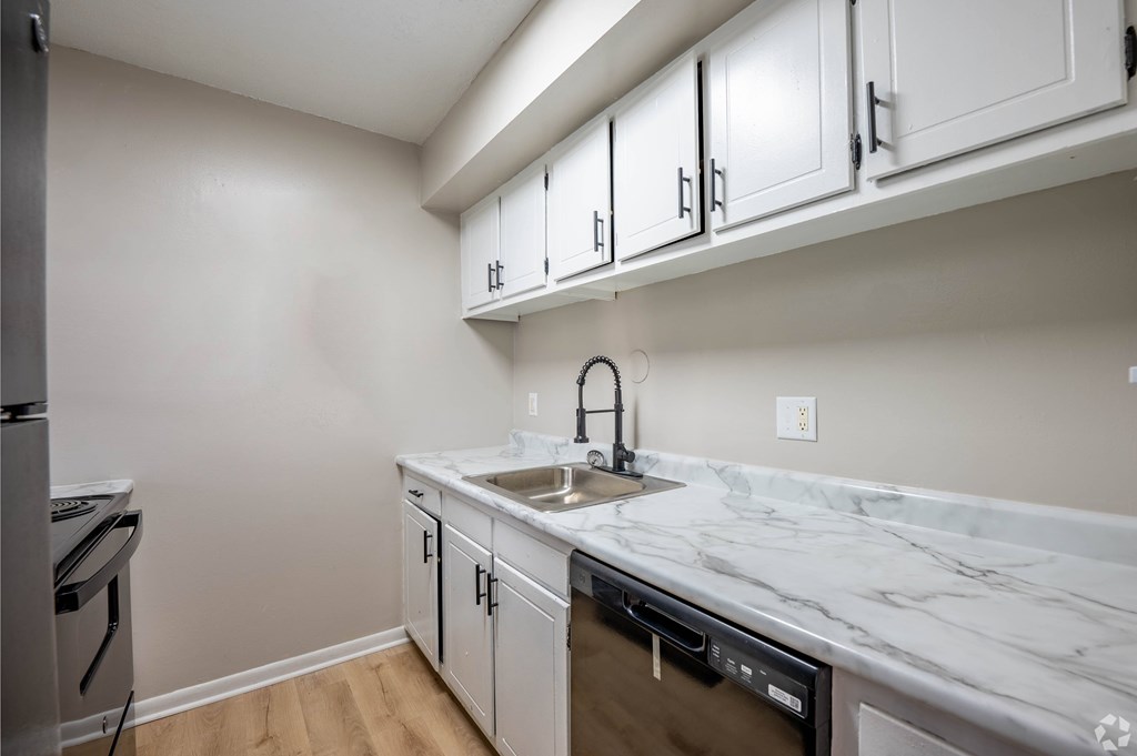 A kitchen with a marble countertop and white cabinets.