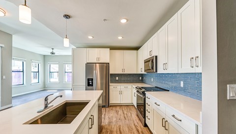 A modern kitchen with white cabinets and a wooden floor.