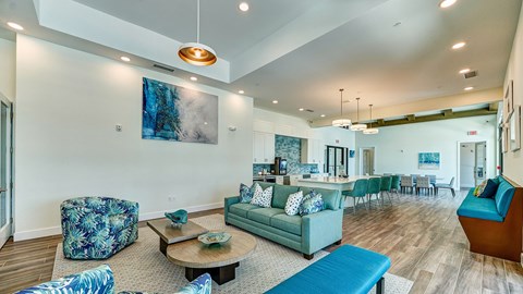A living room with a blue couch and a painting on the wall.
