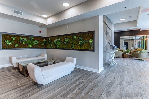 A living room with a large painting of green plants on the wall.