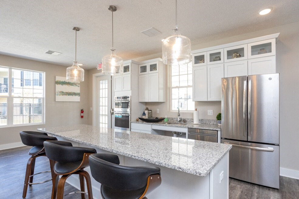 a kitchen with a marble counter top and a stainless steel refrigerator