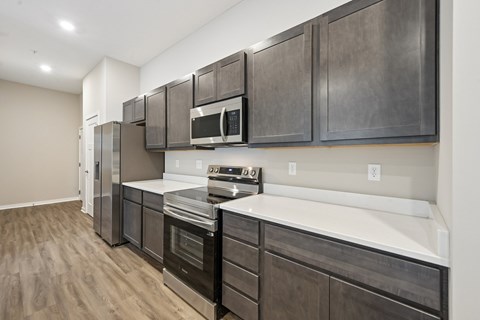 A modern kitchen with dark wood cabinets and stainless steel appliances.