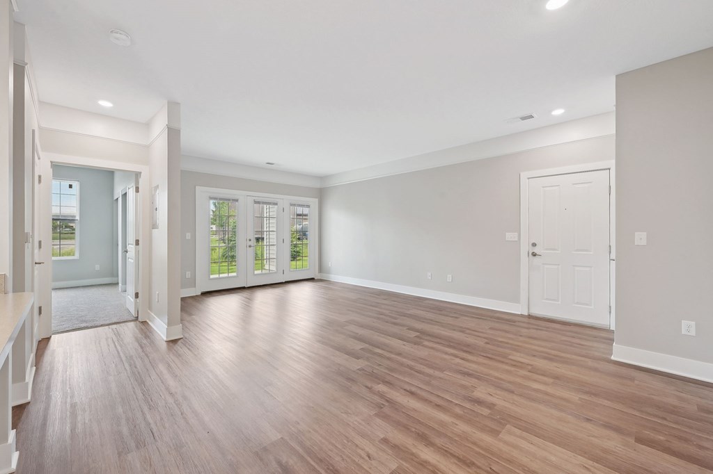 A spacious room with wooden flooring and white walls.
