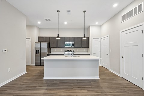 A modern kitchen with a white island and wooden floors.