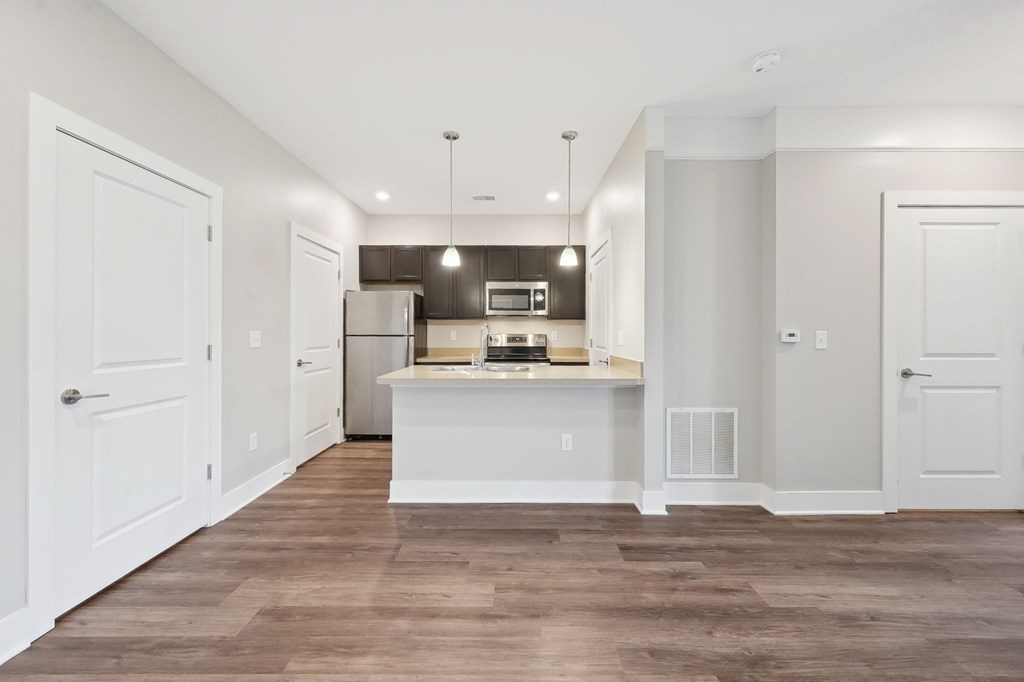 A kitchen with white cabinets and a wooden floor.