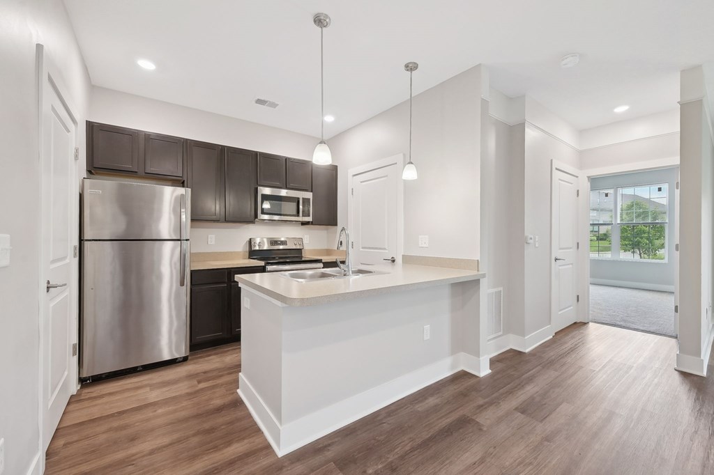 A modern kitchen with a white island and wooden floors.