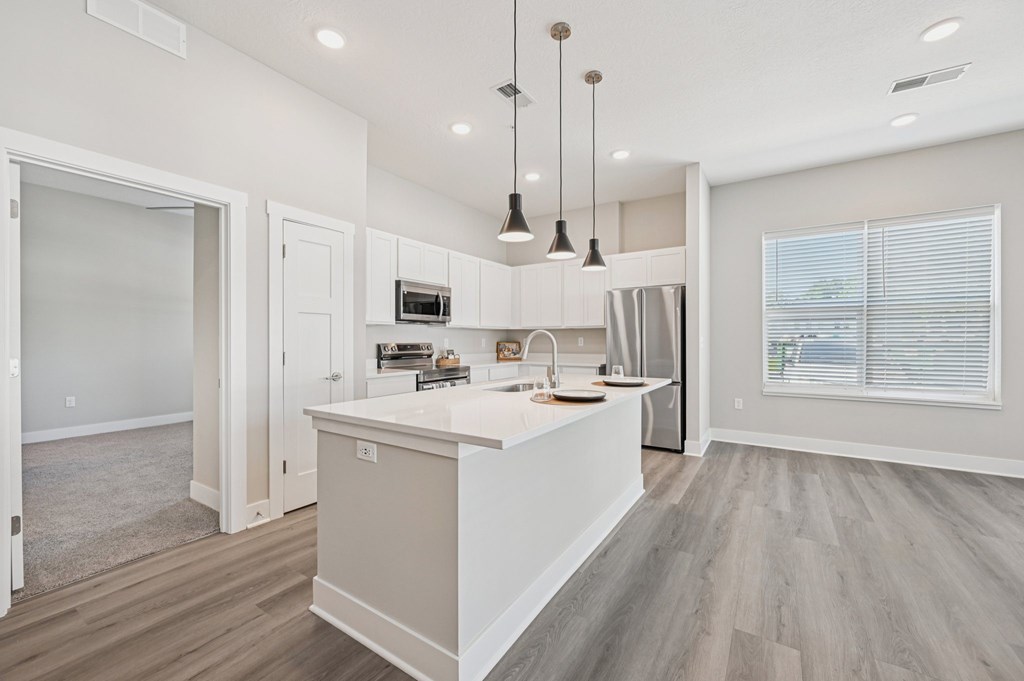 A modern kitchen with a white island and wooden floors.