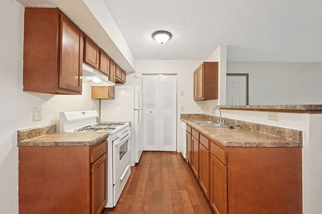 A kitchen with brown cabinets and a white fridge.